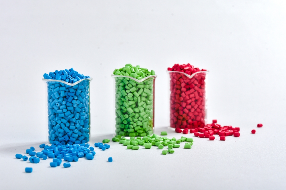 blue,,green,and,red,masterbatch,granules,in,measuring,cup,isolated